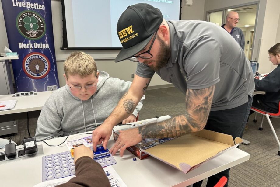 Riley Waters helps a student assemble an electrical circuit board Dec. 19, 2024, after giving a presentation on how students can become electricians through the local IBEW union at Southeastern Community College during its annual 8th Grade Career Fair in West Burlington.